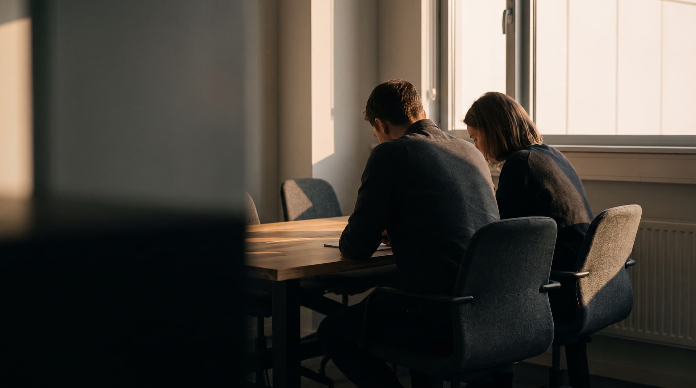 Zwei Menschen arbeiten nebeneinander an einem Tisch
